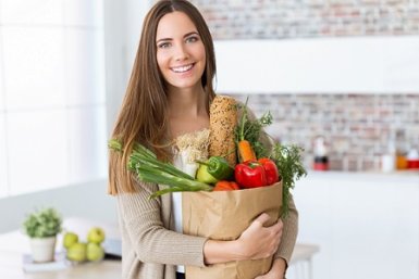 young woman with vegetables in grocery bag at home