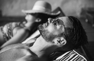 A couple on vacation sun bathing on the beach chair