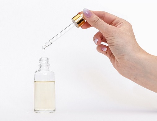 Dropper glass Bottle Mock-Up. Oily drop falls from cosmetic pipette on white background.