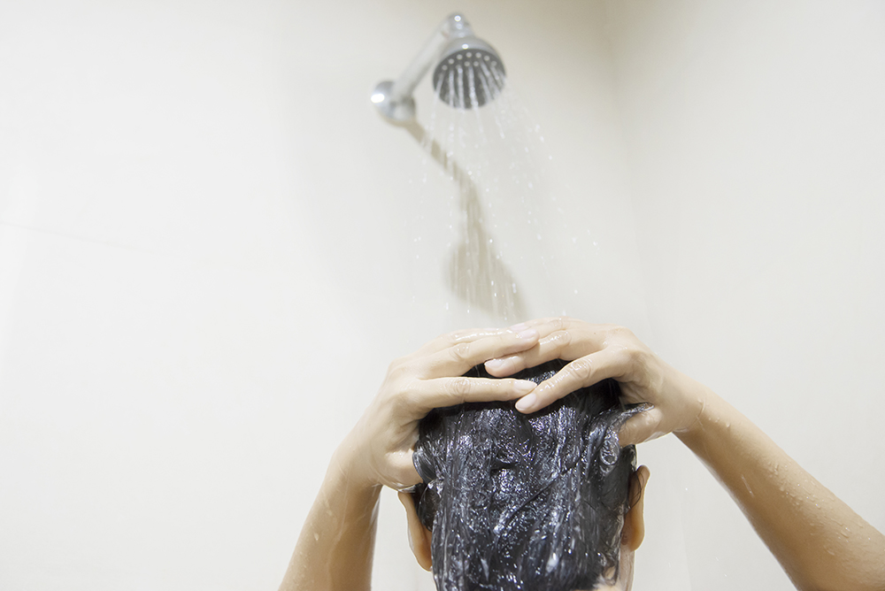 Lady using shampoo wash / clean her hair in a bathroom with splash shower spray water