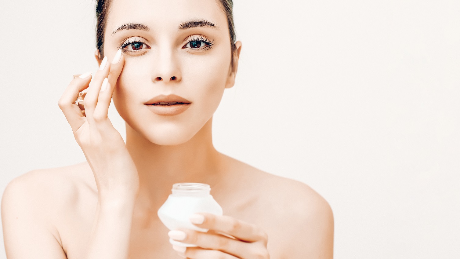 Natural beauty portrait of young woman applying cream on her face