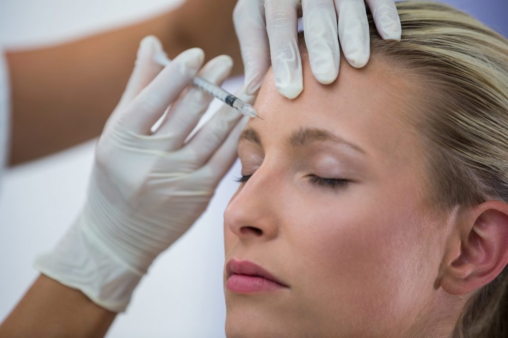 Close-up of female patient receiving a botox injection on forehead